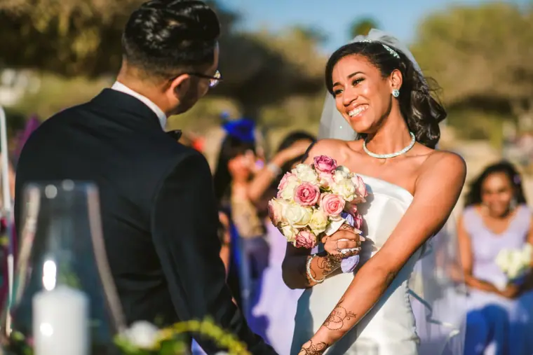 Smiling bride holding her rose bouquet at the ceremony