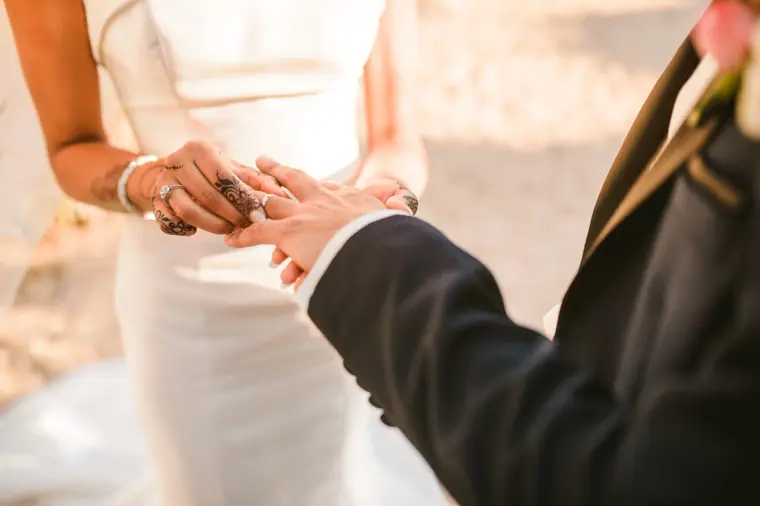 Bride's hennaed hand resting in the groom's, showing her wedding ring