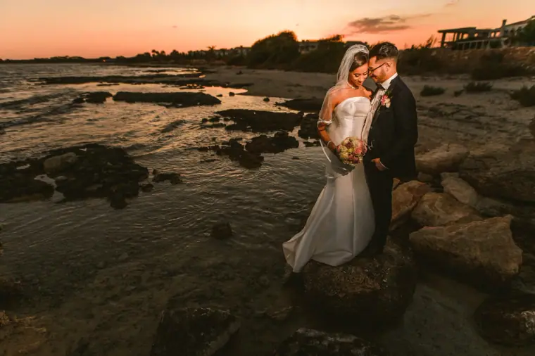 Couple embracing among rock pools along the shore at dusk