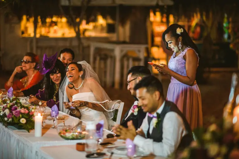 Bride covering her mouth in laughter at the top table during speeches