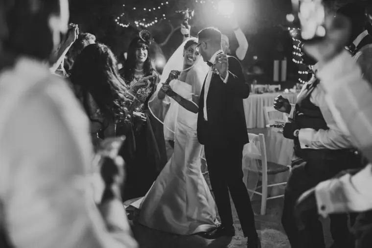 Black-and-white photo of bride and groom dancing among guests