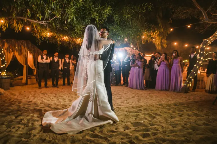 Groom twirling the bride during their first dance as bridesmaids watch