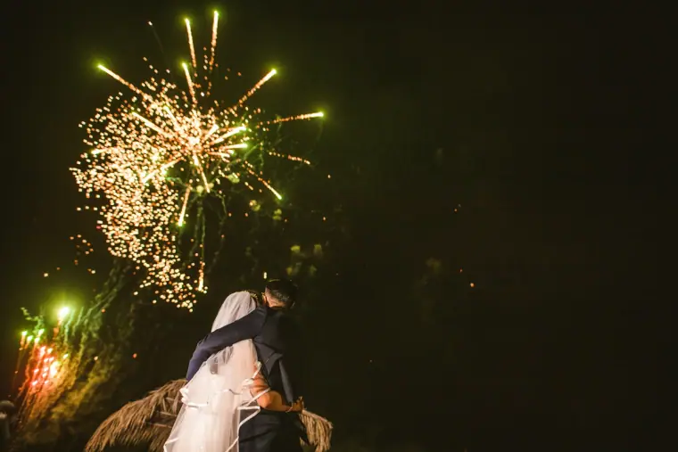 Fireworks bursting above the newlyweds as they kiss in the dark