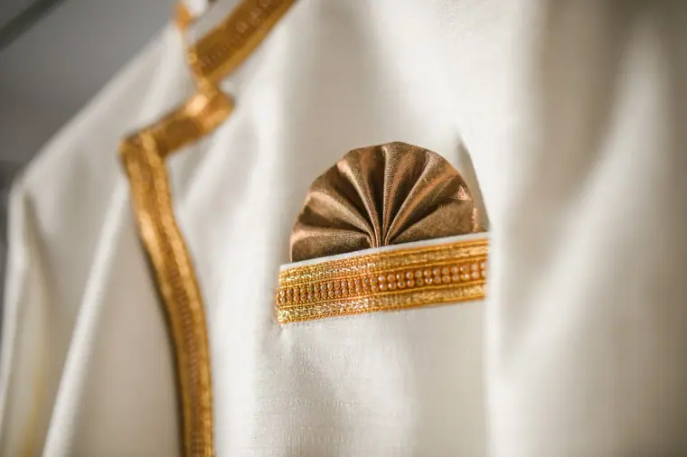 Close-up of a gold fan pocket square on a cream sherwani