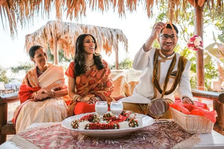 Groom laughing with his hand raised as the bride and a relative sit beside him