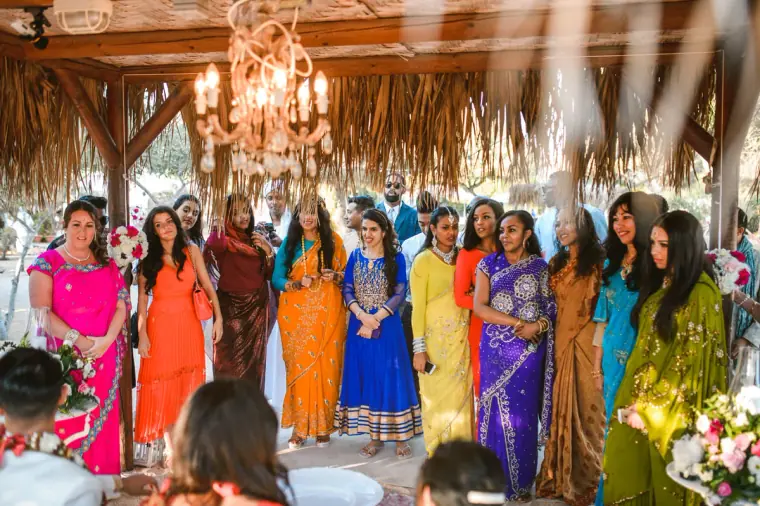 Guests in rainbow-coloured saris gathered beneath the thatched canopy and chandelier