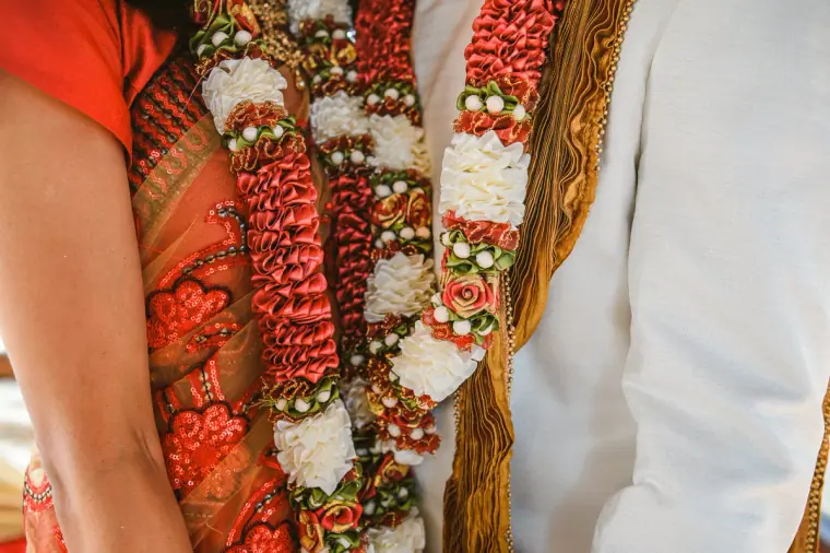 Detail of the couple's red and white flower garlands against her sari and his sherwani