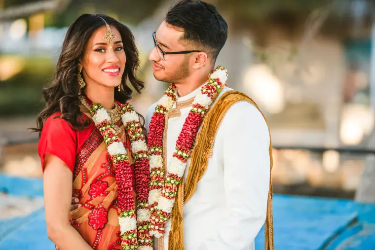 Raya and Adhib in garlands smiling at each other by the sea