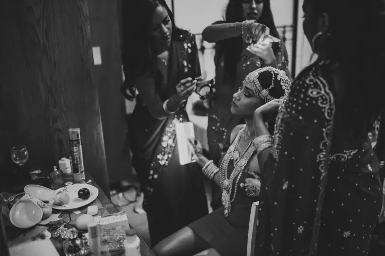 Black-and-white photo of women preparing the bride in her gold headdress