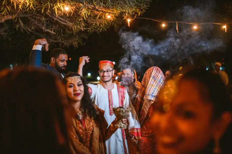 Guests dancing under festoon lights as smoke drifts through the night air