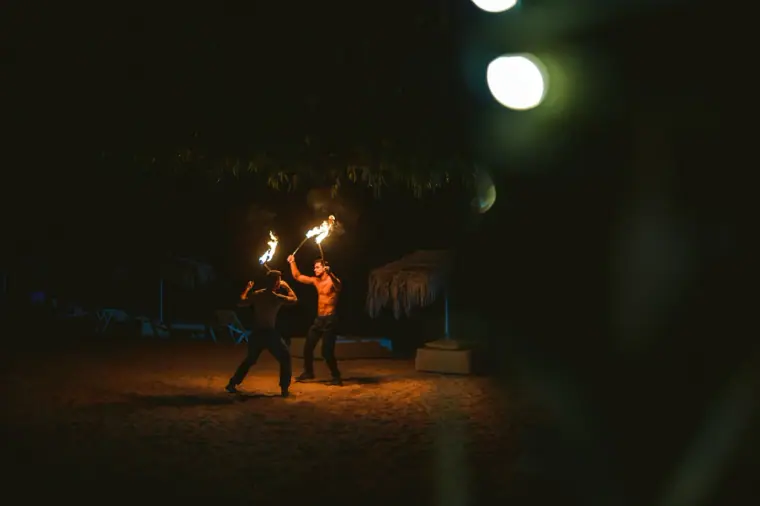 Fire performers spinning flames in the darkness on the beach