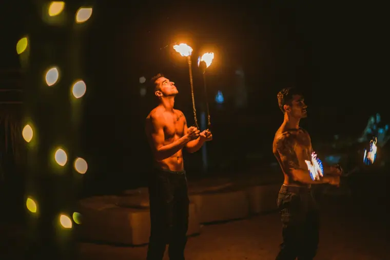Two fire performers juggling flaming torches in the dark
