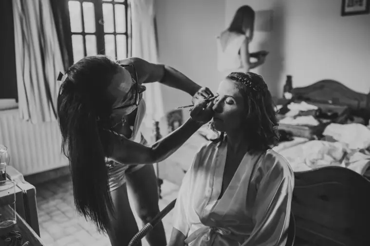 Black-and-white photo of the bride in a robe having her make-up done