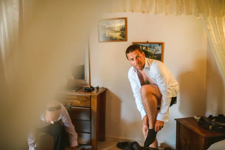 Groom pulling on his socks in a traditional bedroom at the inn