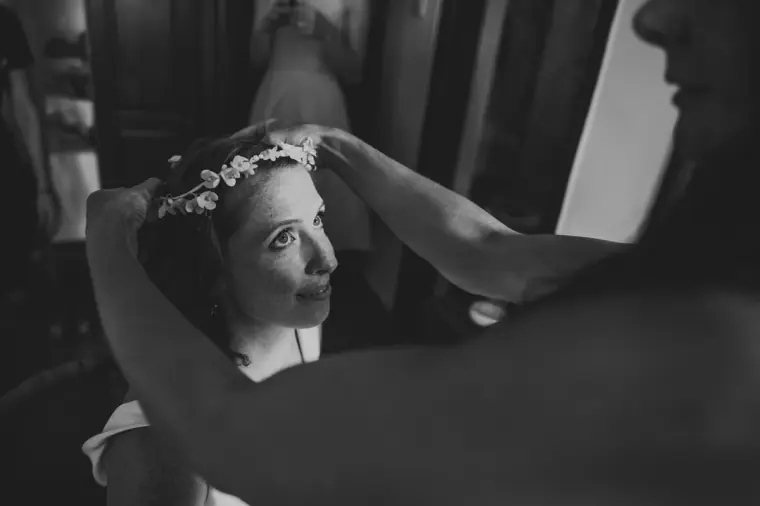 Black-and-white photo of the bride adjusting her flower crown