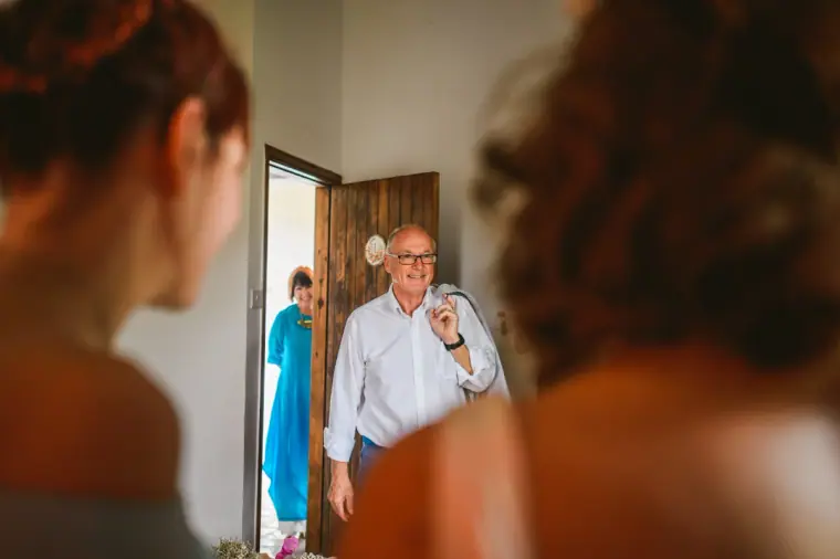 Bride's father arriving at the door as the bride waits, seen past her shoulder