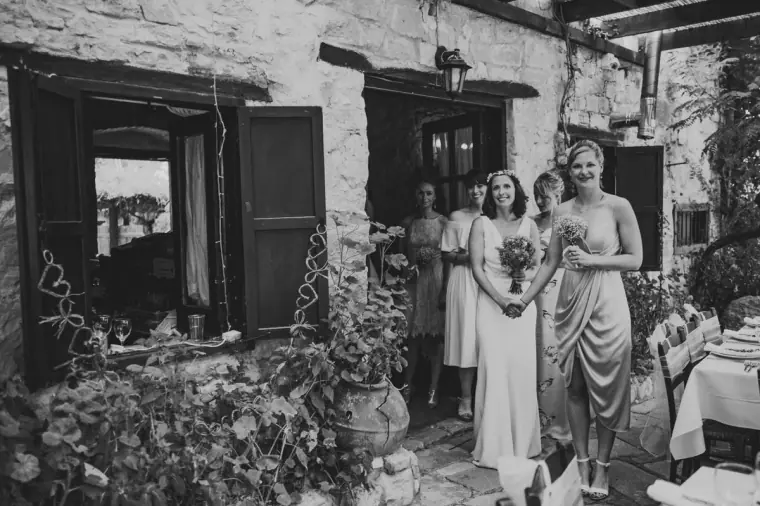 Black-and-white photo of the bride and bridesmaids in the stone courtyard before the ceremony