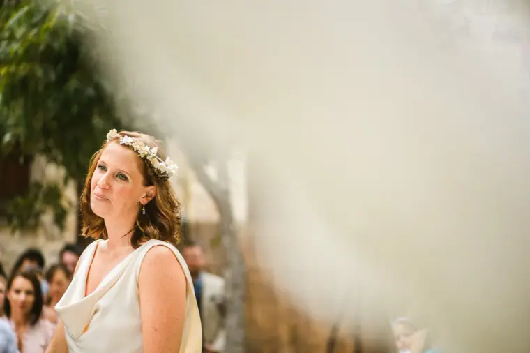 Fleur in a flower crown glancing up at the ceremony, framed by soft lace