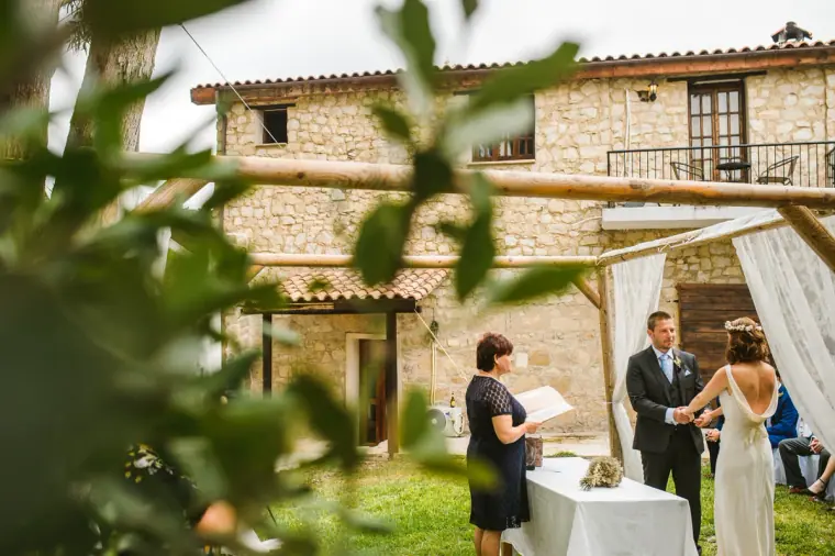 Outdoor ceremony in the garden of Vasilias Nikoklis Inn, seen through leaves