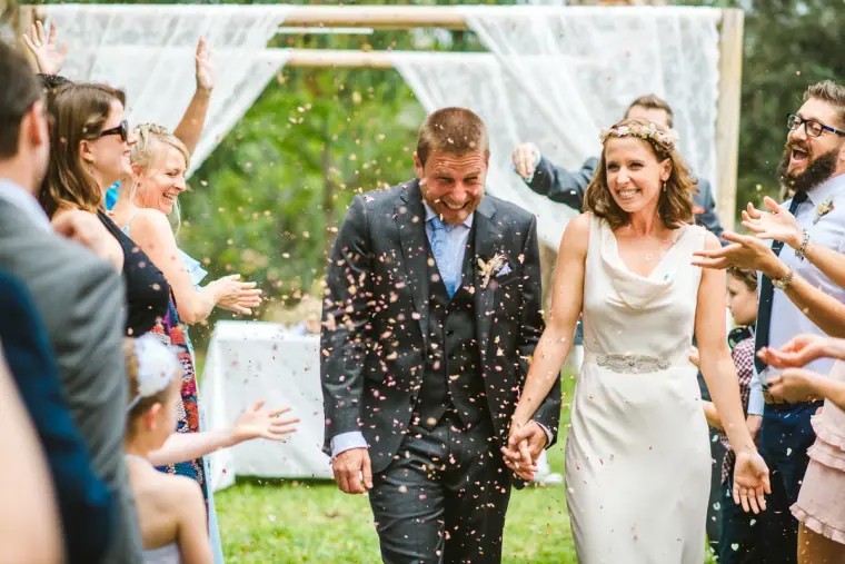 Newlyweds walking hand in hand through a shower of confetti
