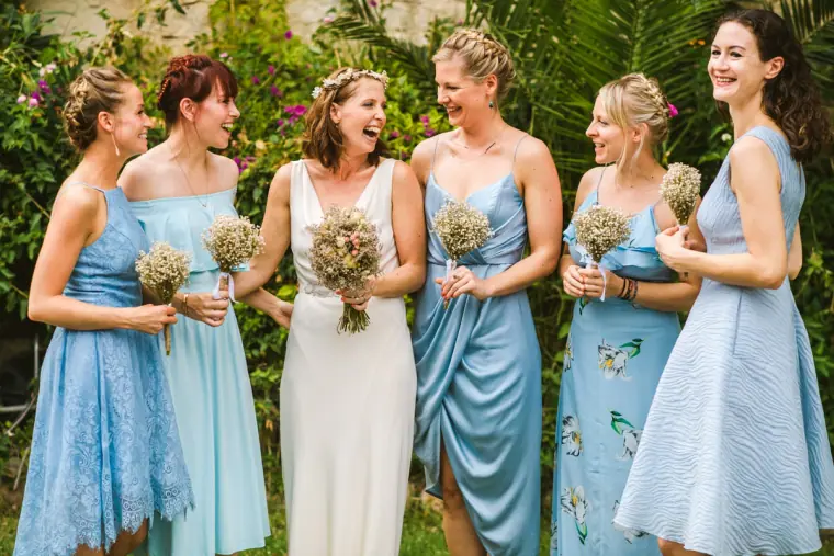 Bride laughing with her bridesmaids in assorted pale blue dresses