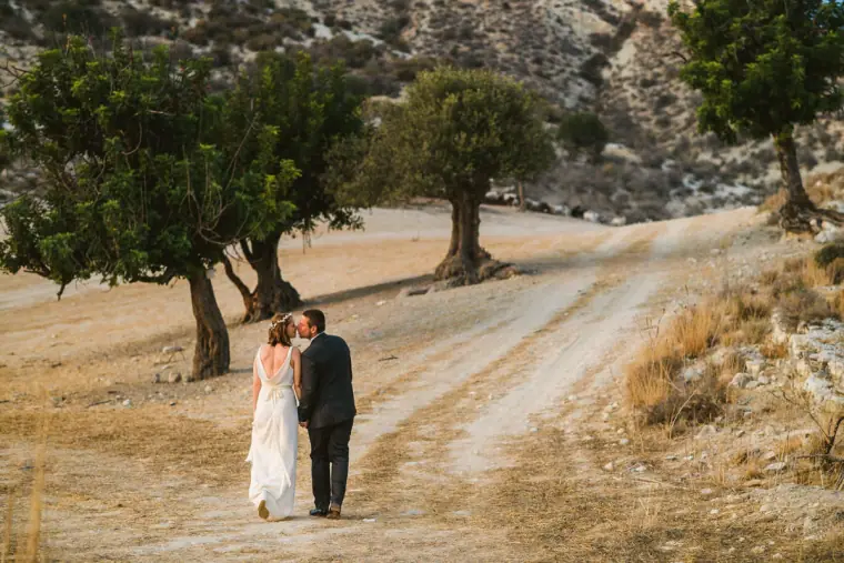 Fleur and Kazem kissing on a dirt track lined with carob trees near Nikokleia