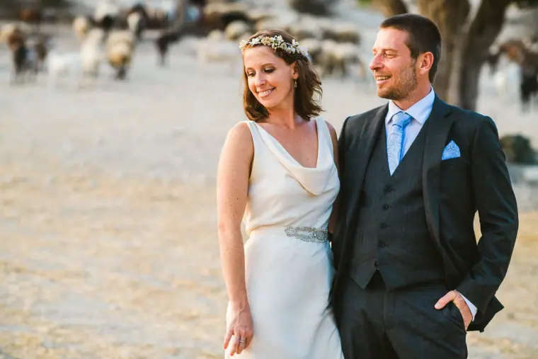 Fleur and Kazem smiling together as a herd of goats grazes behind them