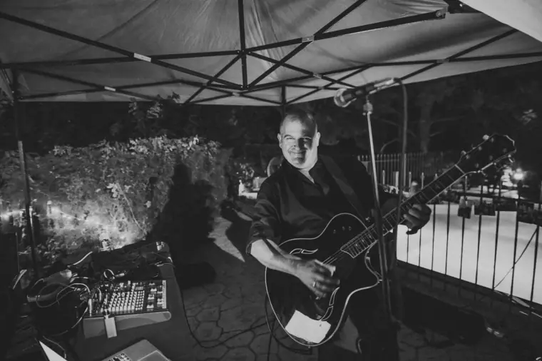 Black-and-white photo of a guitarist performing under a gazebo at the reception