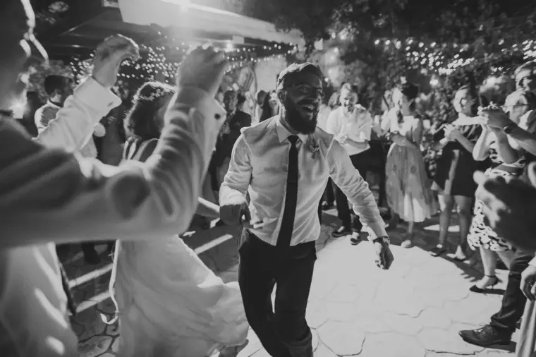 Black-and-white photo of a guest dancing energetically on the stone courtyard