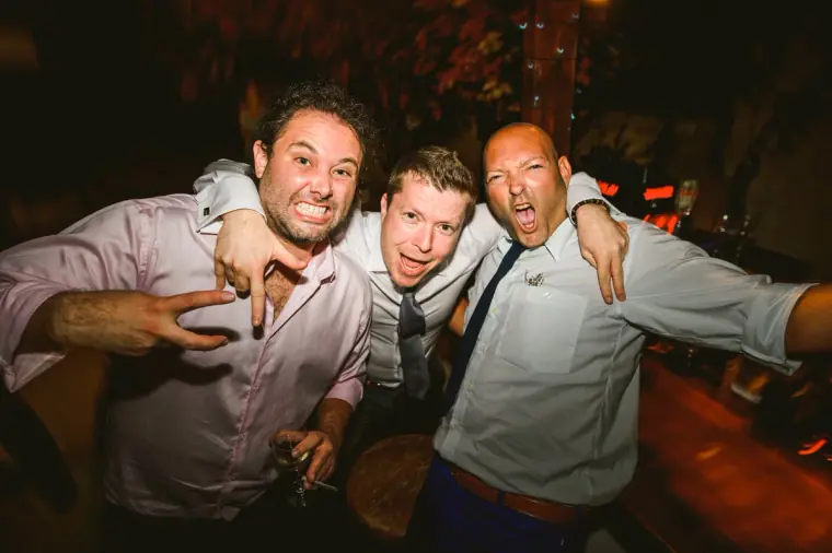 Three male guests pulling faces and posing on the dance floor