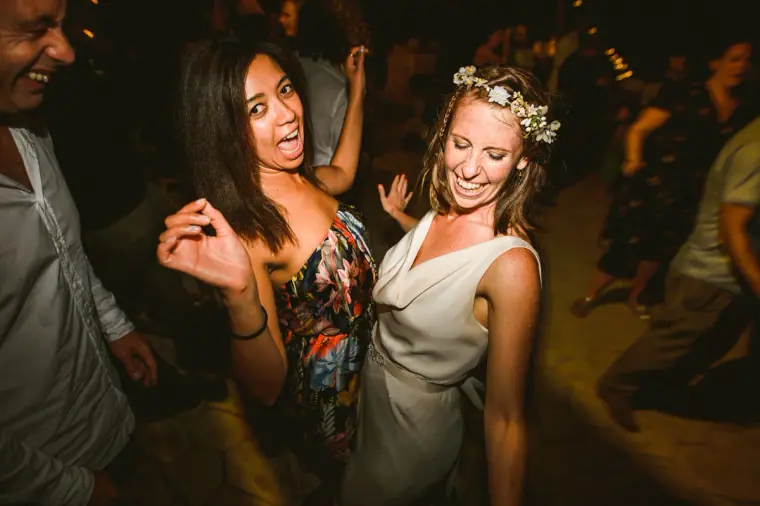 Bride in a flower crown dancing with a friend in a floral dress