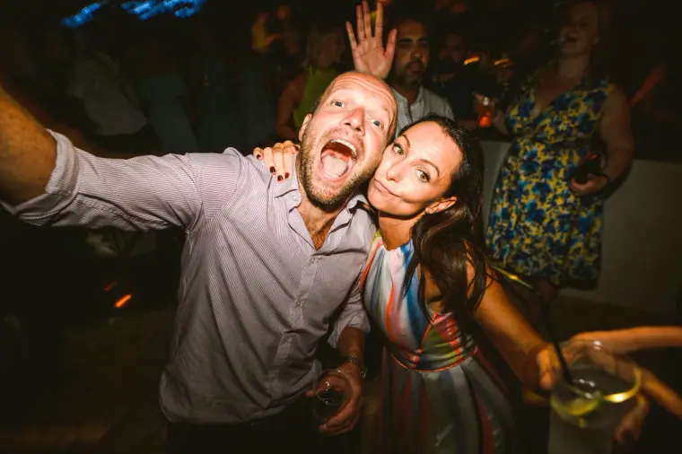 Two guests taking a wide-angle selfie-style pose on the dance floor