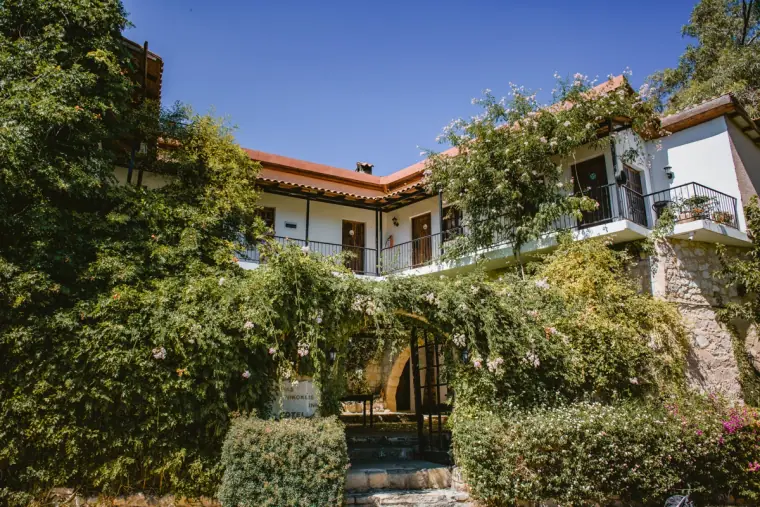 Vasilias Nikoklis Inn's stone and whitewashed buildings behind lush gardens