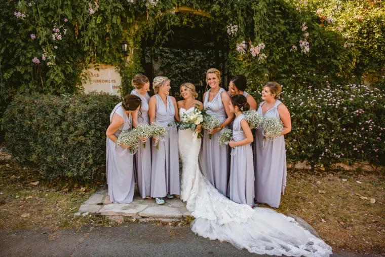 Bride in a long-trained lace gown with bridesmaids holding gypsophila bouquets