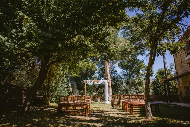 Rows of wooden chairs set for the ceremony beneath tall trees in the inn's garden