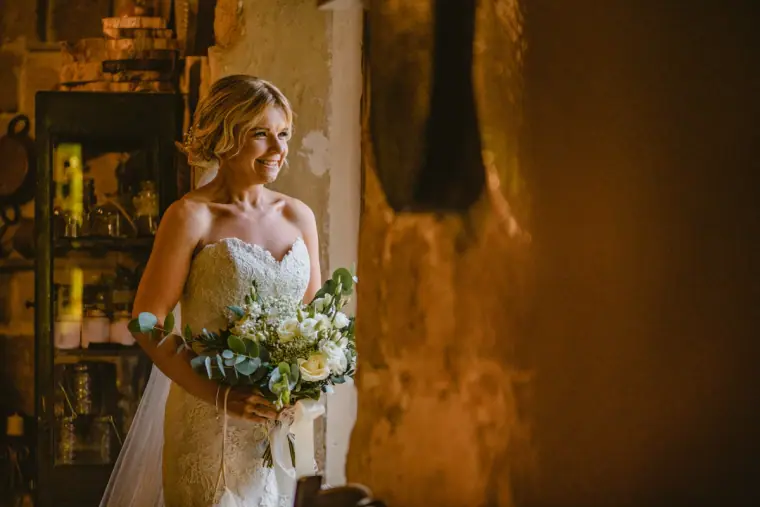 Bride holding her bouquet in a warmly lit doorway before the ceremony