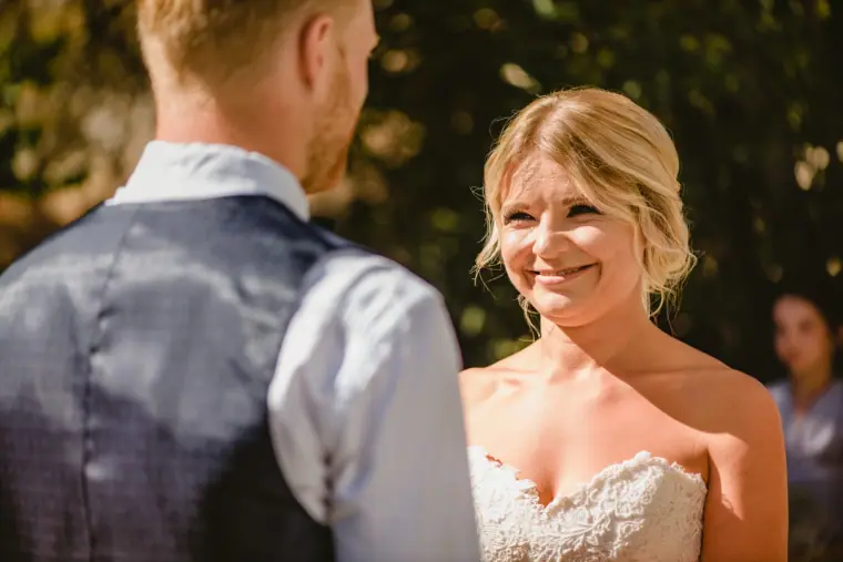 Fiona smiling at Paul during their ceremony, seen over his shoulder