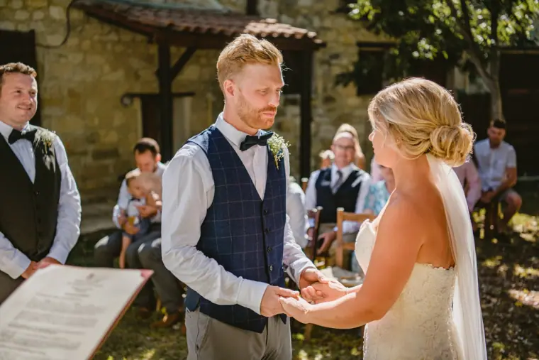 Bride and groom holding hands at the ceremony as guests look on