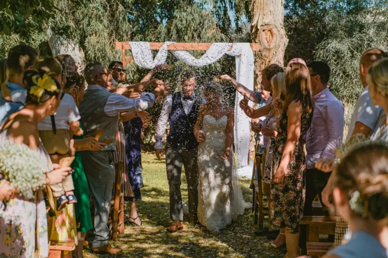 Newlyweds walking back up the aisle through confetti thrown by guests