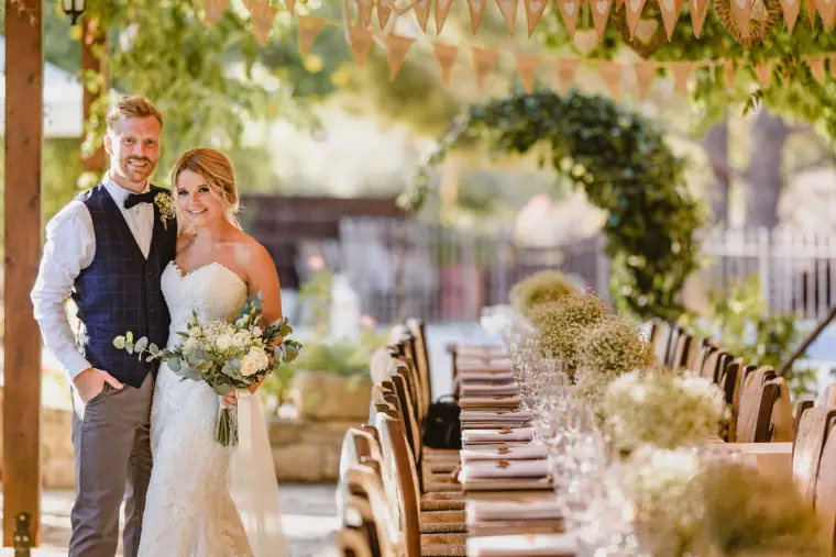 Couple posing beside the long reception table dressed with gypsophila