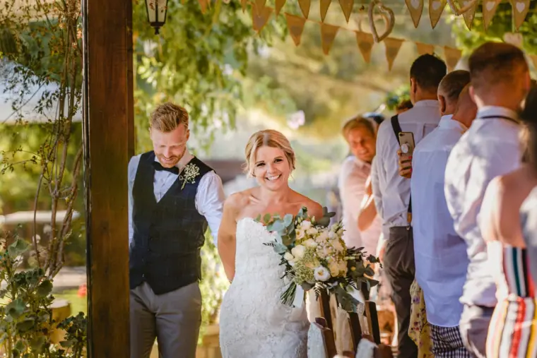 Bride and groom chatting with guests under the bunting-draped pergola