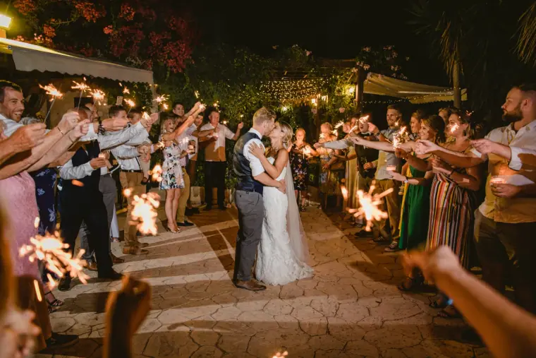 Newlyweds walking through a tunnel of guests holding sparklers at night