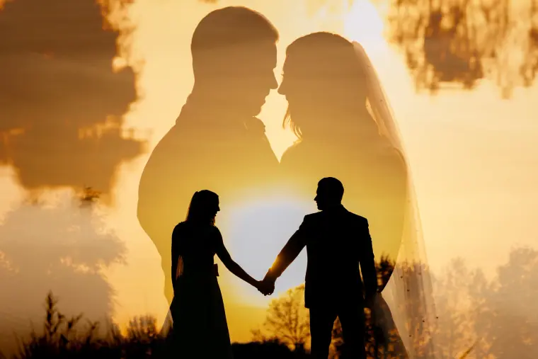 Double exposure of a couple's silhouettes holding hands against a golden sunset, Wokefield Park