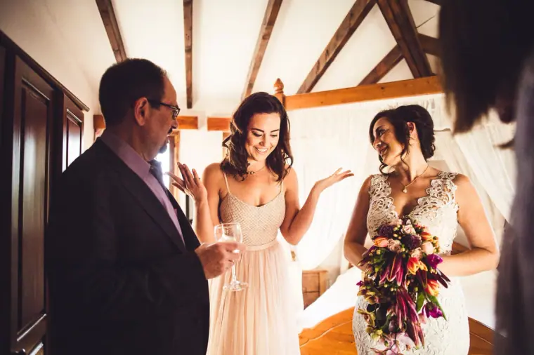 Bride and bridesmaid laughing as a relative looks on before the ceremony