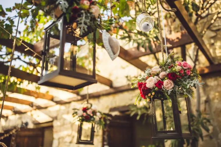 Lanterns with roses hanging from the wooden pergola above the courtyard