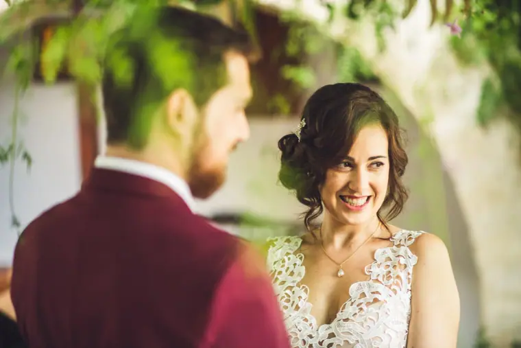 Bride smiling at the groom during the ceremony, seen over his shoulder