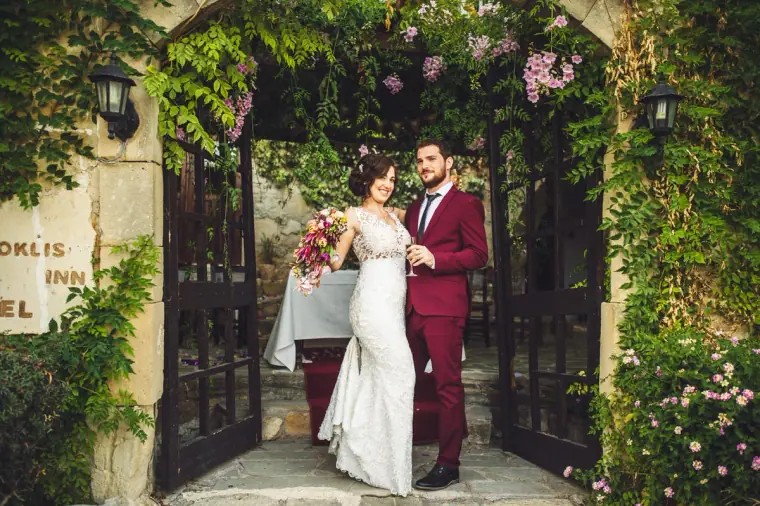 Newlyweds walking out through the ivy-covered stone archway of Vasilias Nikoklis Inn