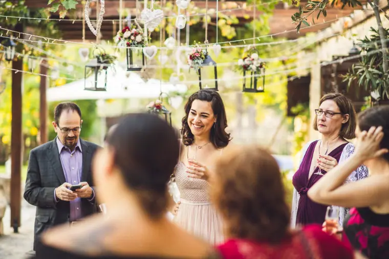 Guests chatting with the bride beneath hanging lanterns after the ceremony