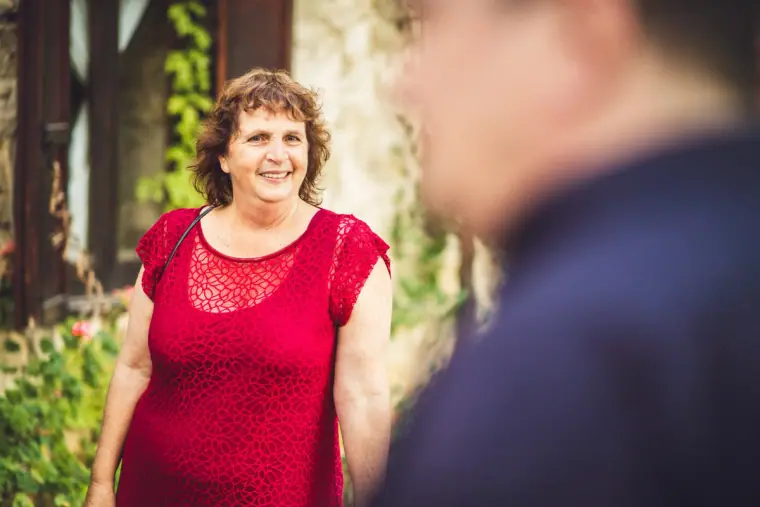 Smiling guest in a red lace dress at the courtyard drinks reception