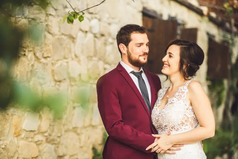 Bride and groom embracing against an old stone wall at Vasilias Nikoklis Inn